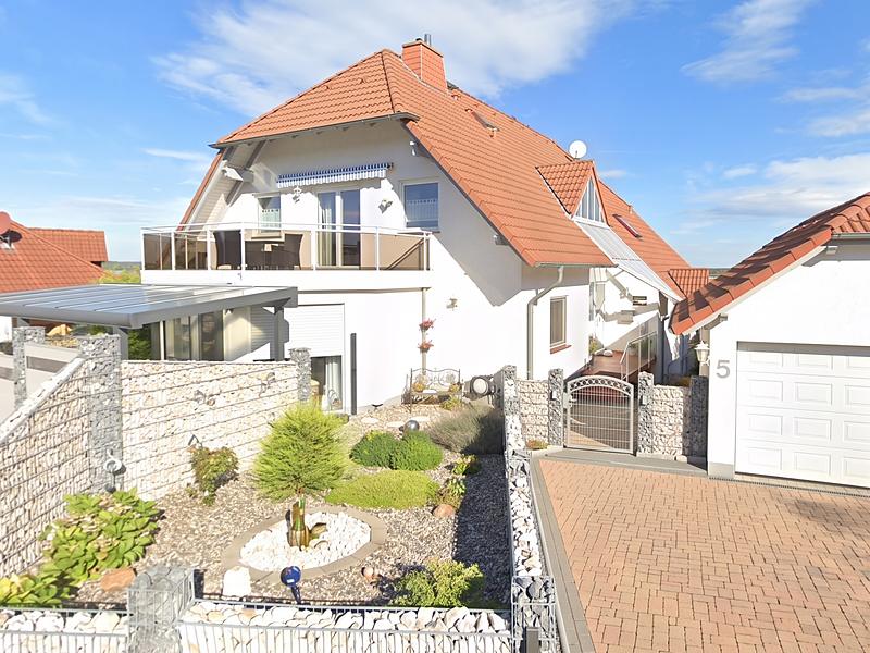 Haus Lipsberg: weißes Wohnhaus mit rotem Satteldach, großem Balkon und angelegtem Vorgarten